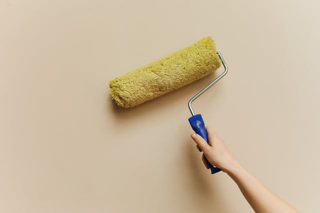 Person using a paint roller on a wall